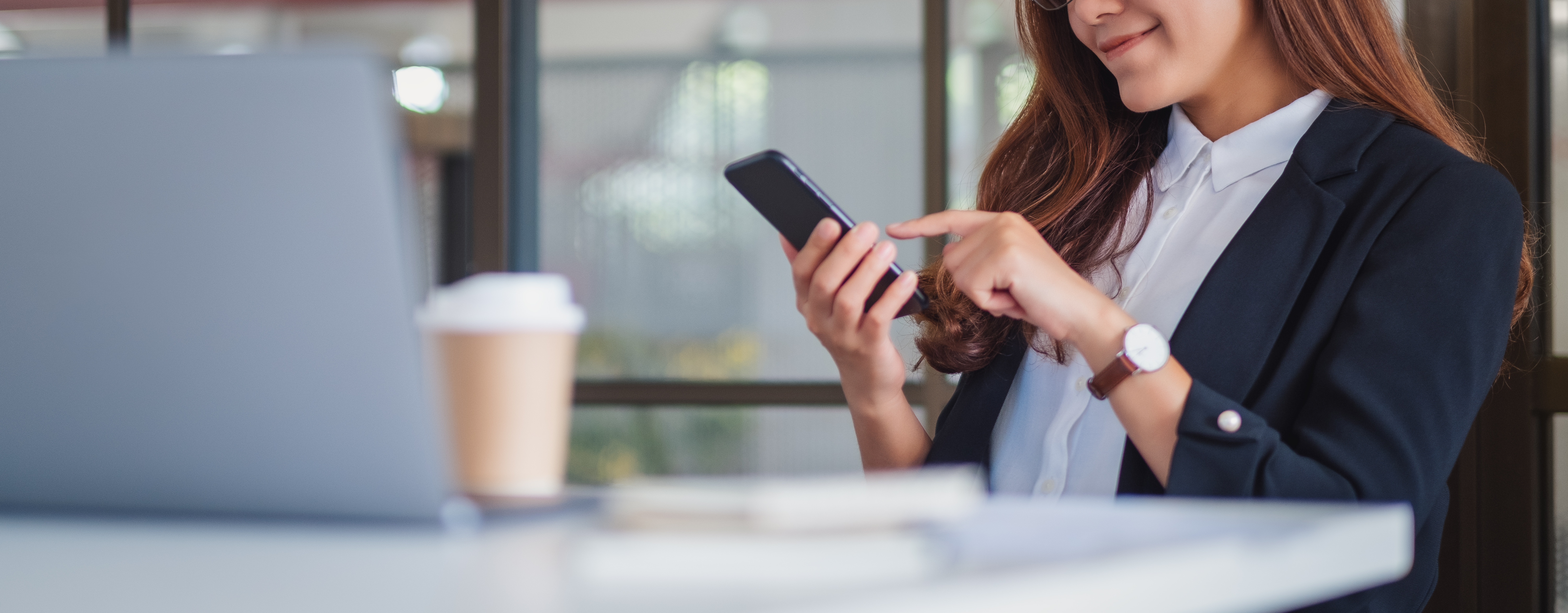 woman working on her phone with laptop next to her